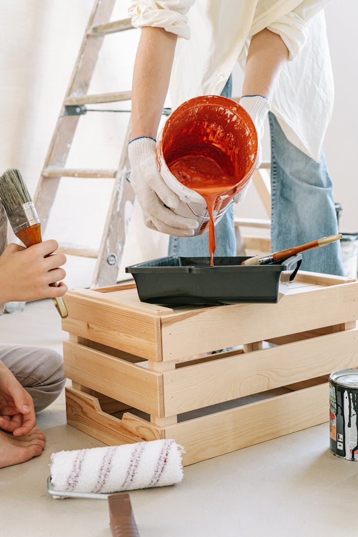 Close-up of people preparing paint and tools for a home renovation project indoors.